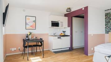 Un espace de vie compact comprenant une kitchenette, un coin repas et un lit.