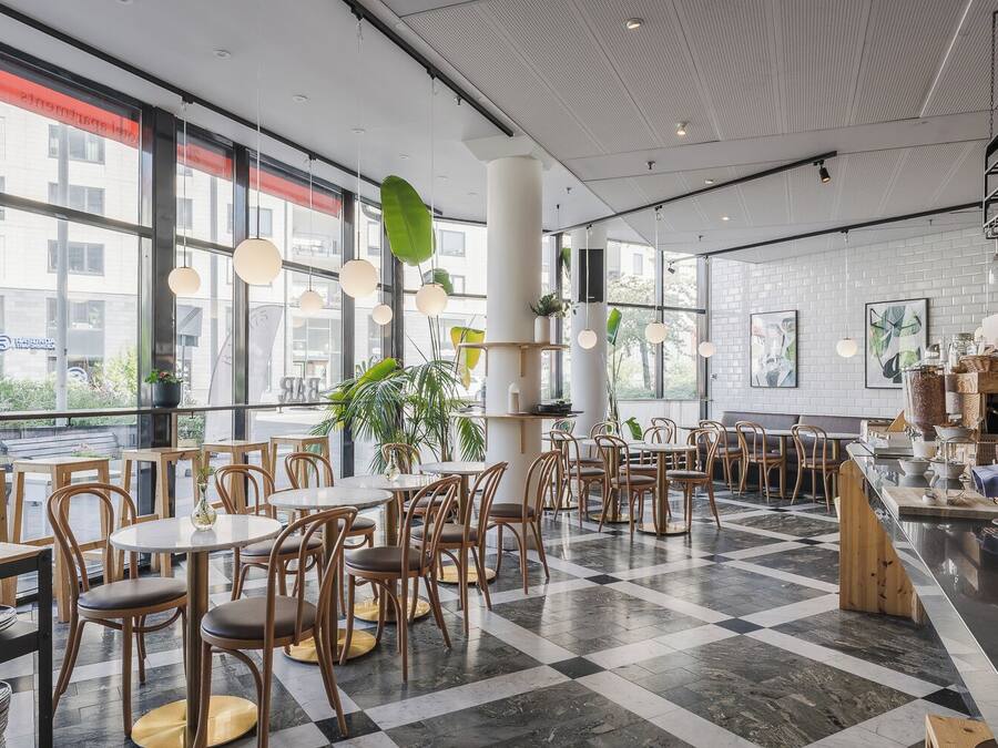A modern cafe with round tables and chairs, large windows, and a checkered floor.