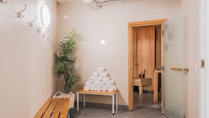 A hallway with a bench, a plant, and a stack of towels. - 2Home Hotel Apartments (Solna)