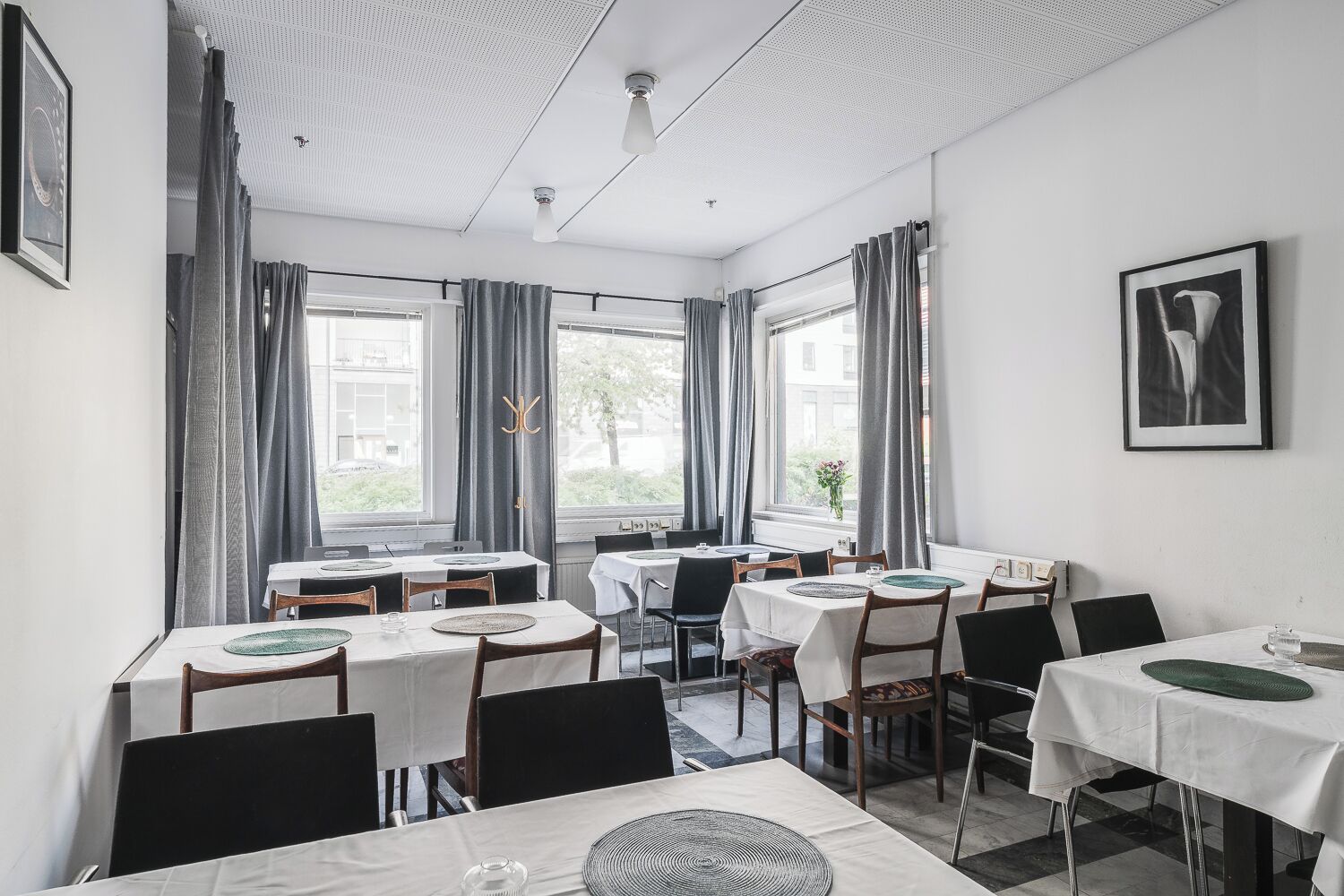 Un comedor con mesas, sillas y ventanas amplias.