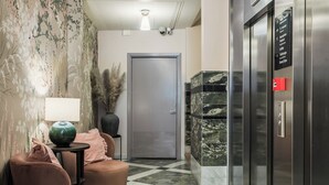 A hotel lobby with a checkered floor, a reception desk, a door, and an elevator. - 2Home Hotel Apartments (Solna)