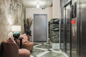 A hotel lobby with a checkered floor, a reception desk, a door, and an elevator. - 2Home Hotel Apartments (Solna)
