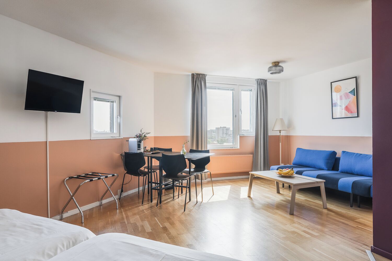 Habitación de hotel con cama, escritorio con sillas, mesa de centro, televisión y sofá.