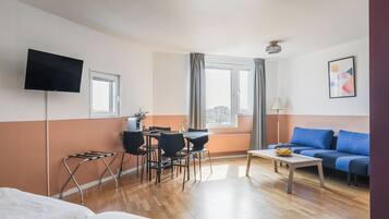 Habitación de hotel con cama, escritorio con sillas, mesa de centro, televisión y sofá.