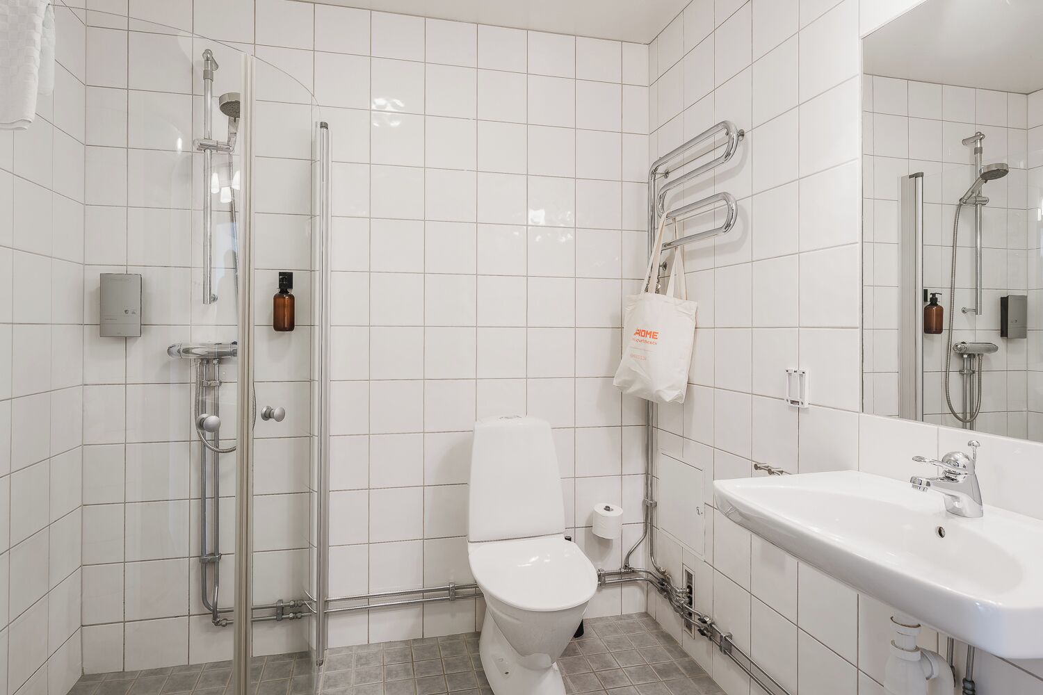 Et moderne badeværelse med brusebad, toilet og håndvask.