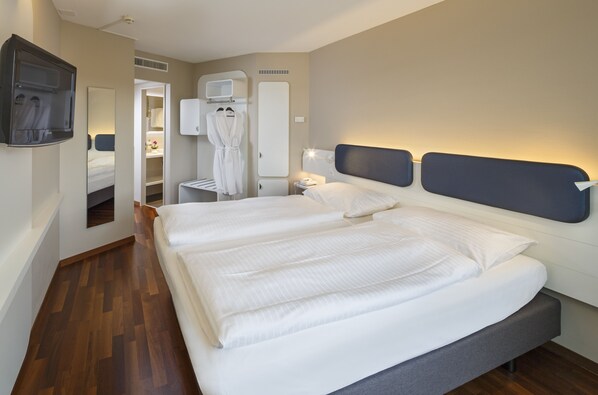 Habitación de hotel con una cama grande, una mesita de noche, televisión, espejo y armario.