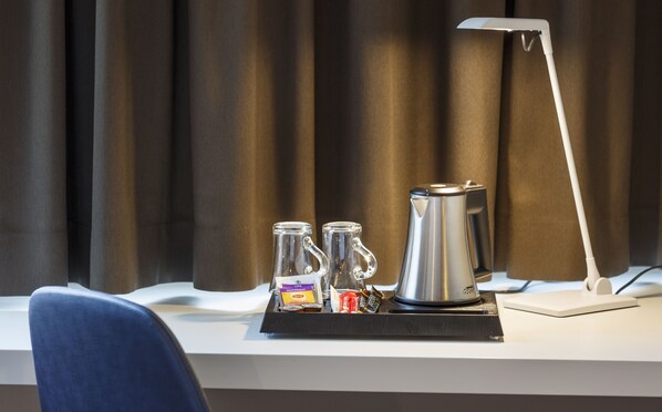 A hotel room with a desk, a coffee maker, two glass mugs, and a tray with condiments. - Hotel Welcome Inn Zurich Airport (Kloten)