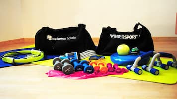 A home gym setup with exercise equipment and bags labeled 'Welcome Hotels' and 'InterSport'.