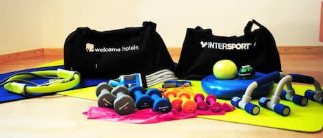 A home gym setup with exercise equipment and bags labeled 'Welcome Hotels' and 'InterSport'.