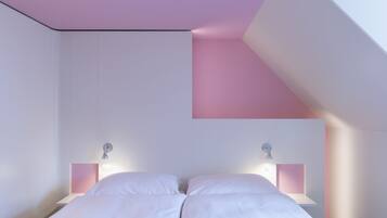 Une chambre à coucher avec un lit placé au centre de la pièce, des murs blancs et un plafond en pente.