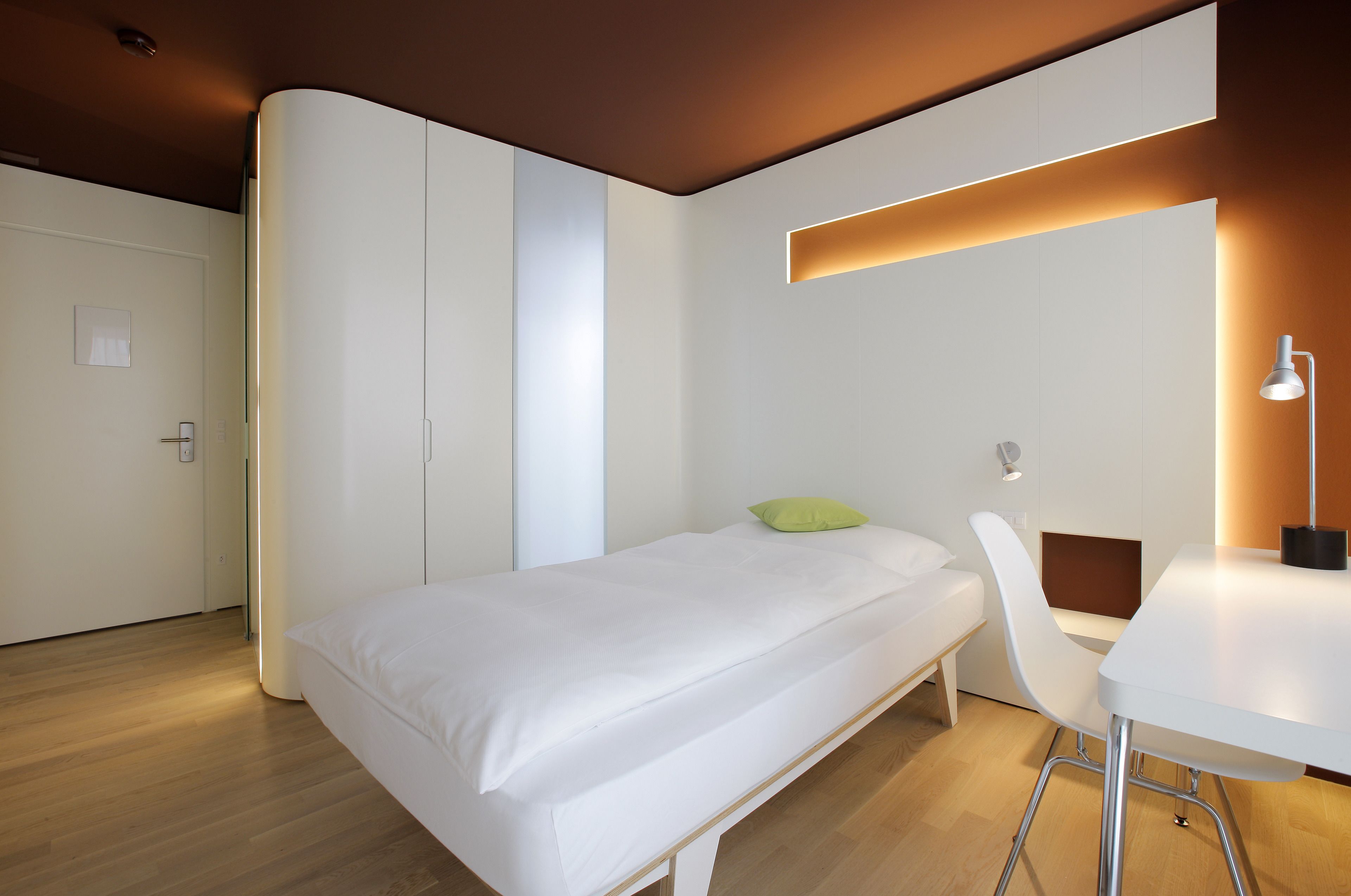 Un dormitorio moderno con una cama, un escritorio y una silla.
