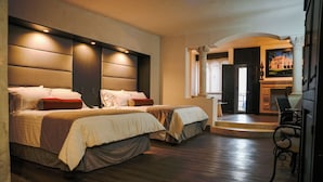 A hotel room with two beds, a dining area, and a view of the outside.