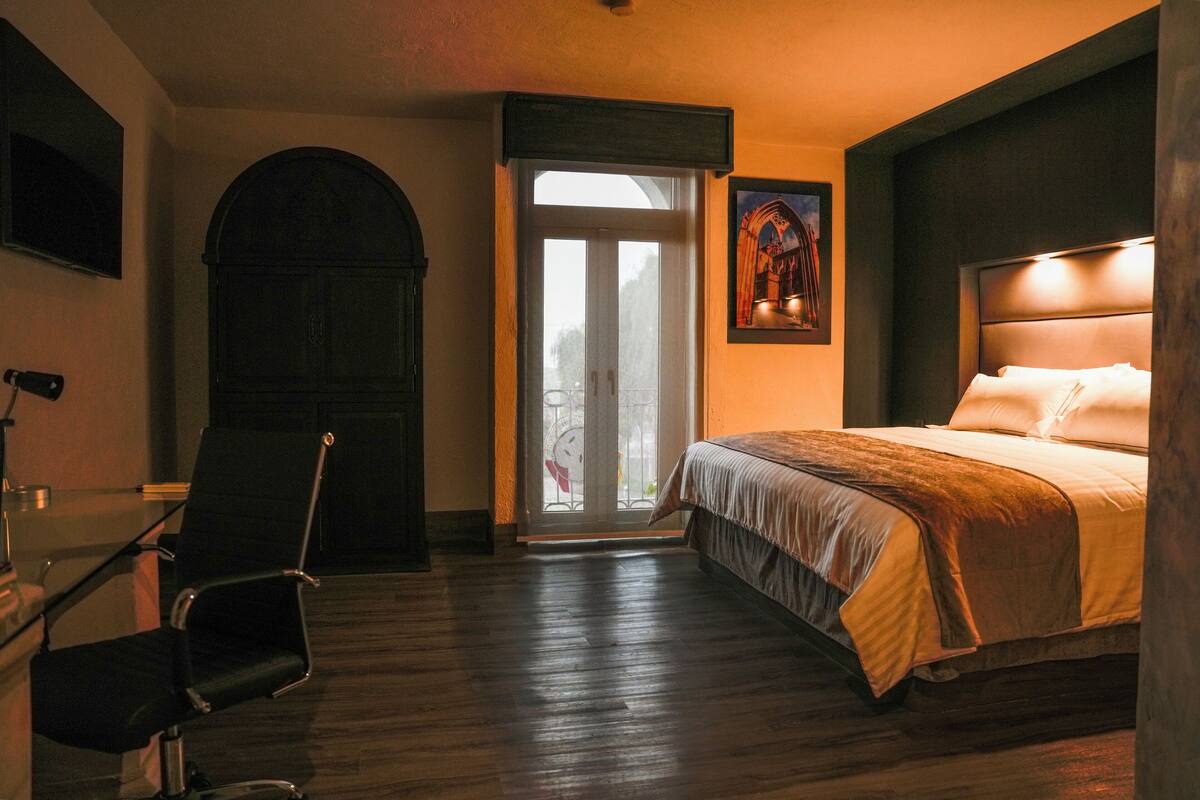 Un dormitorio con una cama, una silla, una puerta y una ventana.