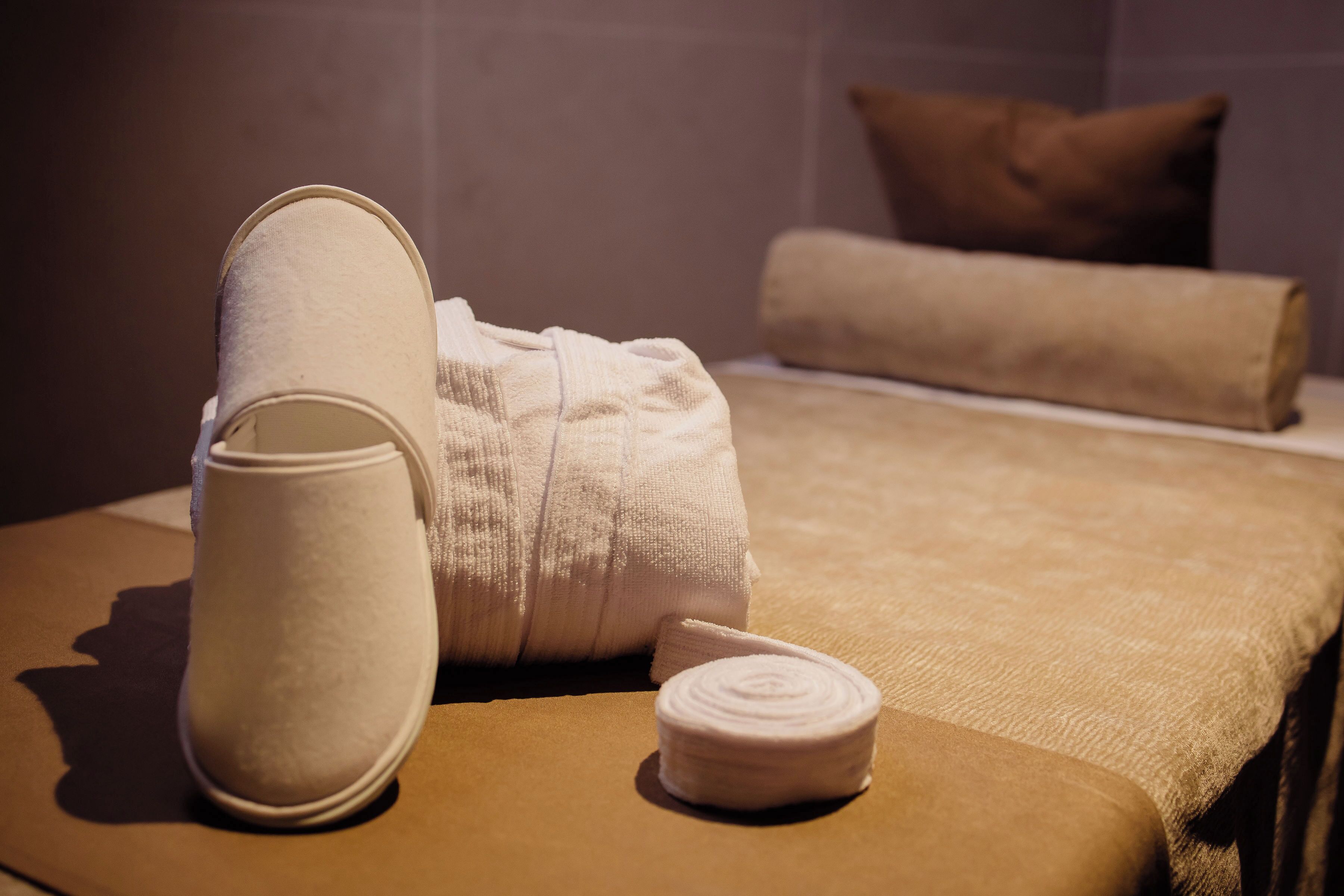 A neatly arranged hotel room with a bed, pillows, and a pair of slippers.