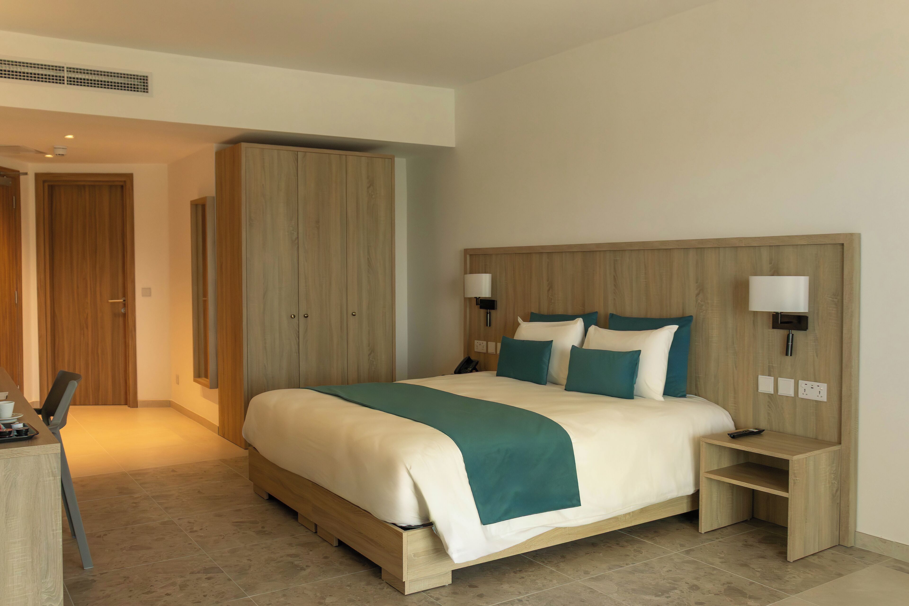 Une chambre d’hôtel comprenant un lit, des tables de chevet, un bureau et une armoire.