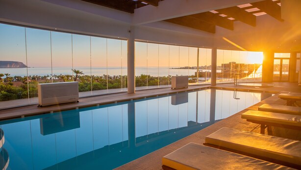 Una piscina con vistas al océano y al atardecer.