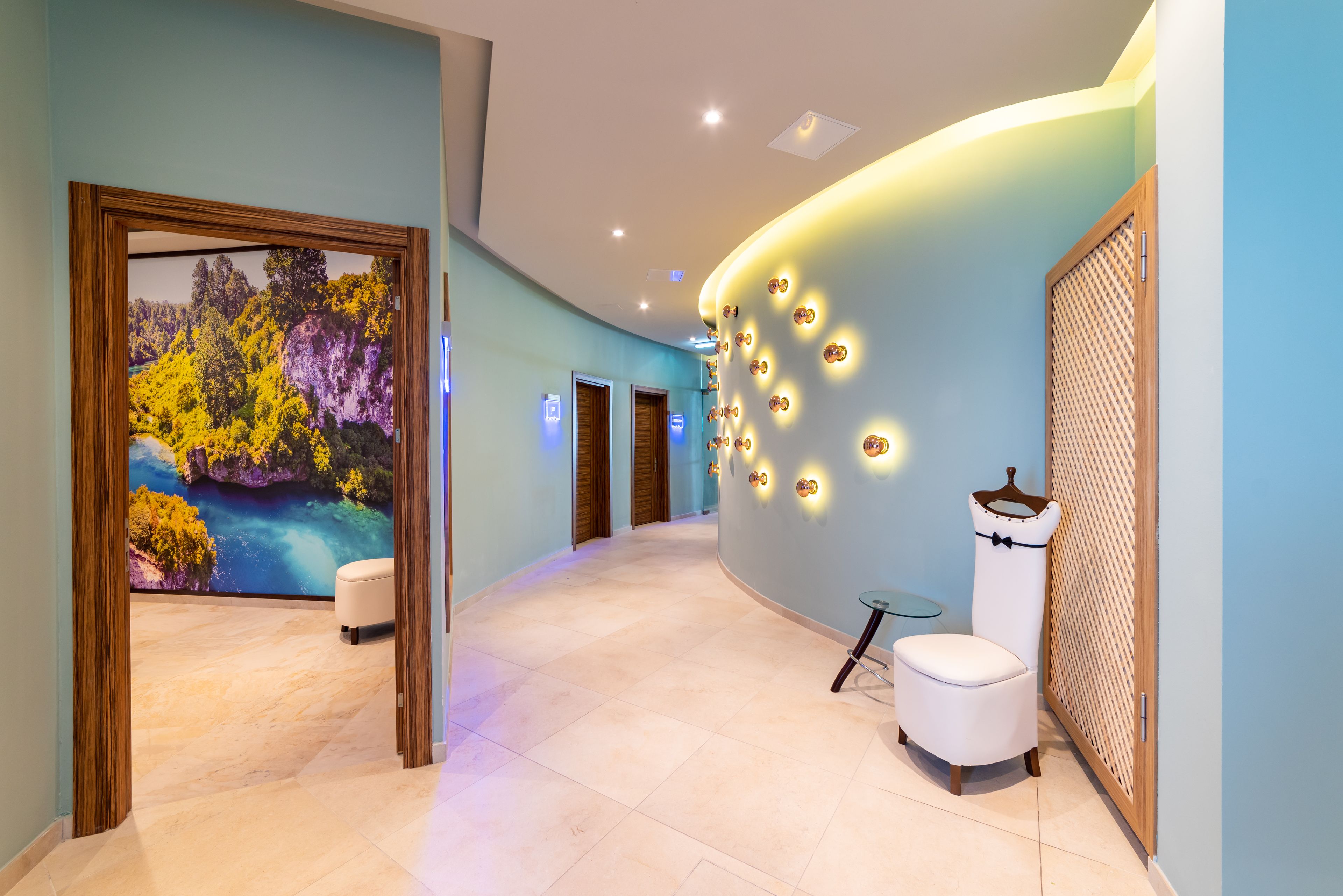 A hallway with a mural, a white bench, and a wall with circular lights.