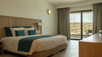 Una habitación de hotel con una cama grande, un escritorio, vistas al paisaje y una ventana con cortinas.