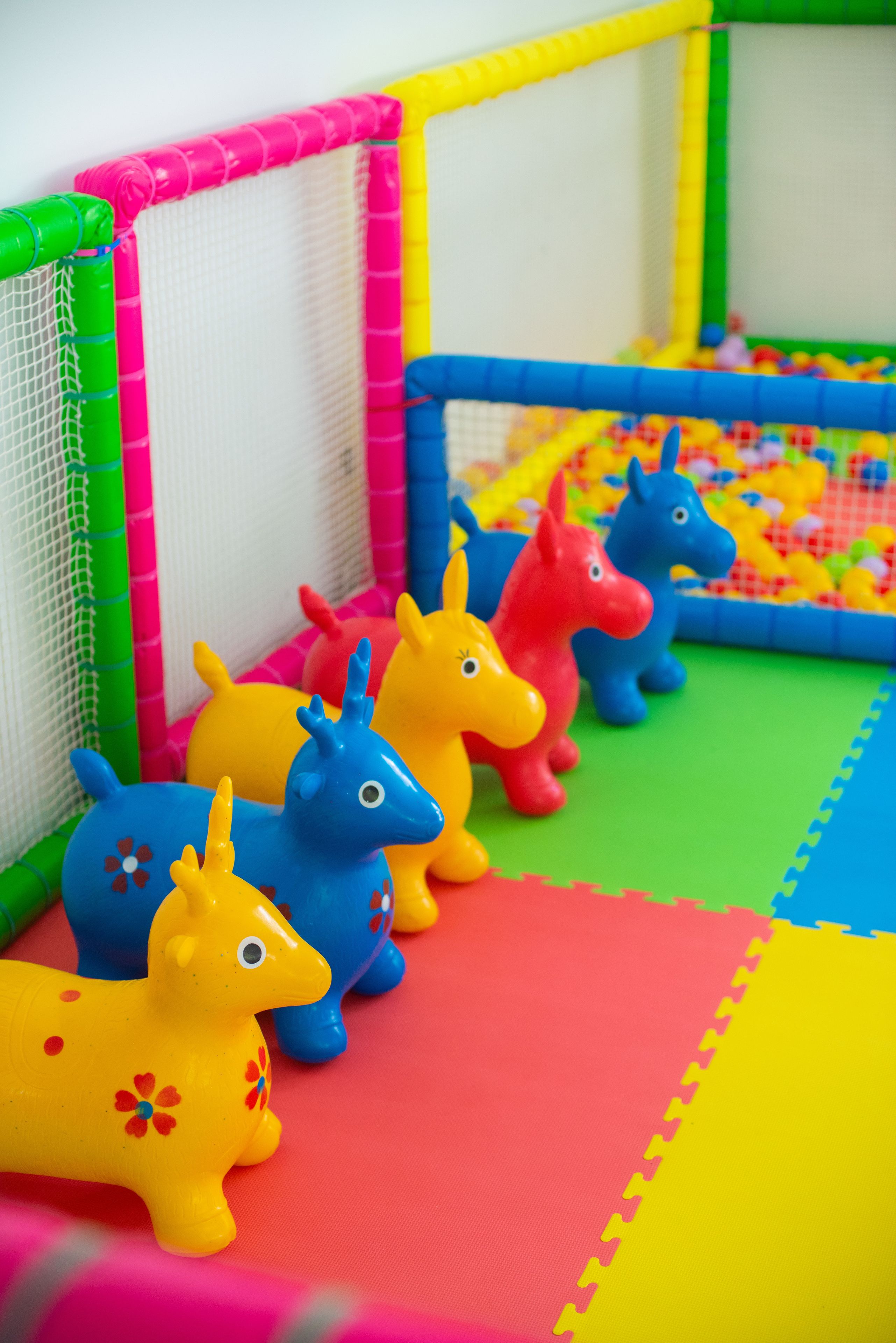 A play area with a safety net and colorful foam mats.