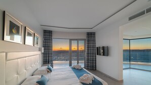 Una habitación de hotel moderna con una cama grande, un televisor de pantalla plana y un balcón con vistas a la ciudad.
