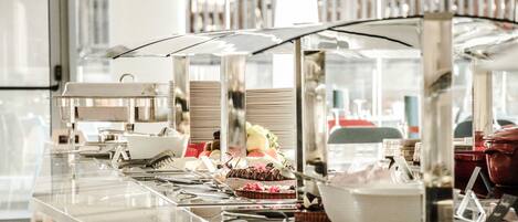 Un buffet avec divers plats et ustensiles disposés sur un comptoir en verre.