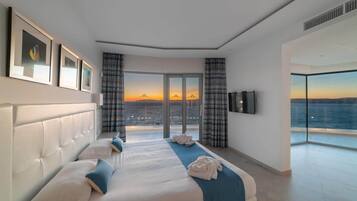 Una habitación de hotel moderna con una cama grande, un televisor de pantalla plana y un balcón con vista a la ciudad.