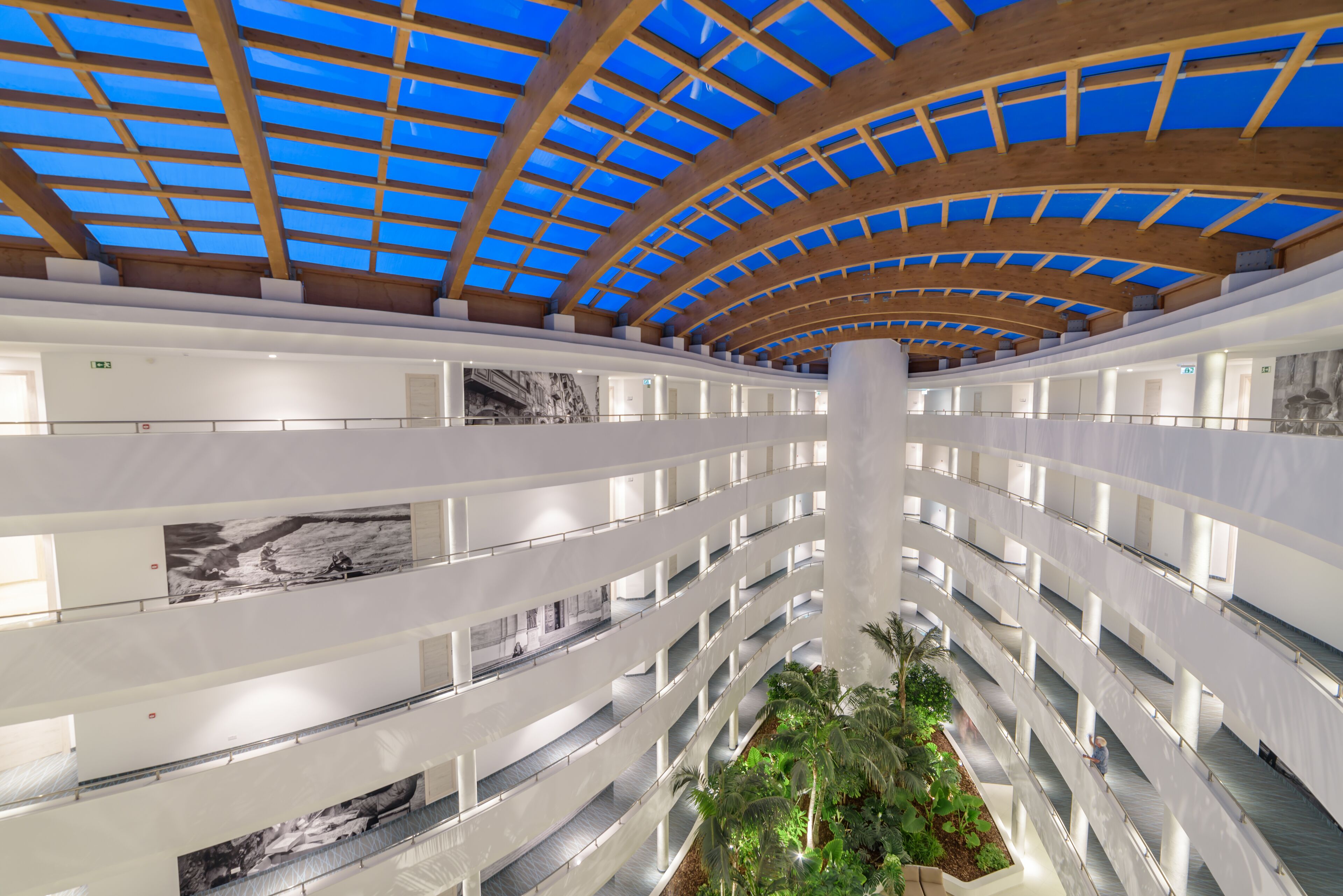 A multi-level atrium with a central open space, multiple balconies, and a glass ceiling.