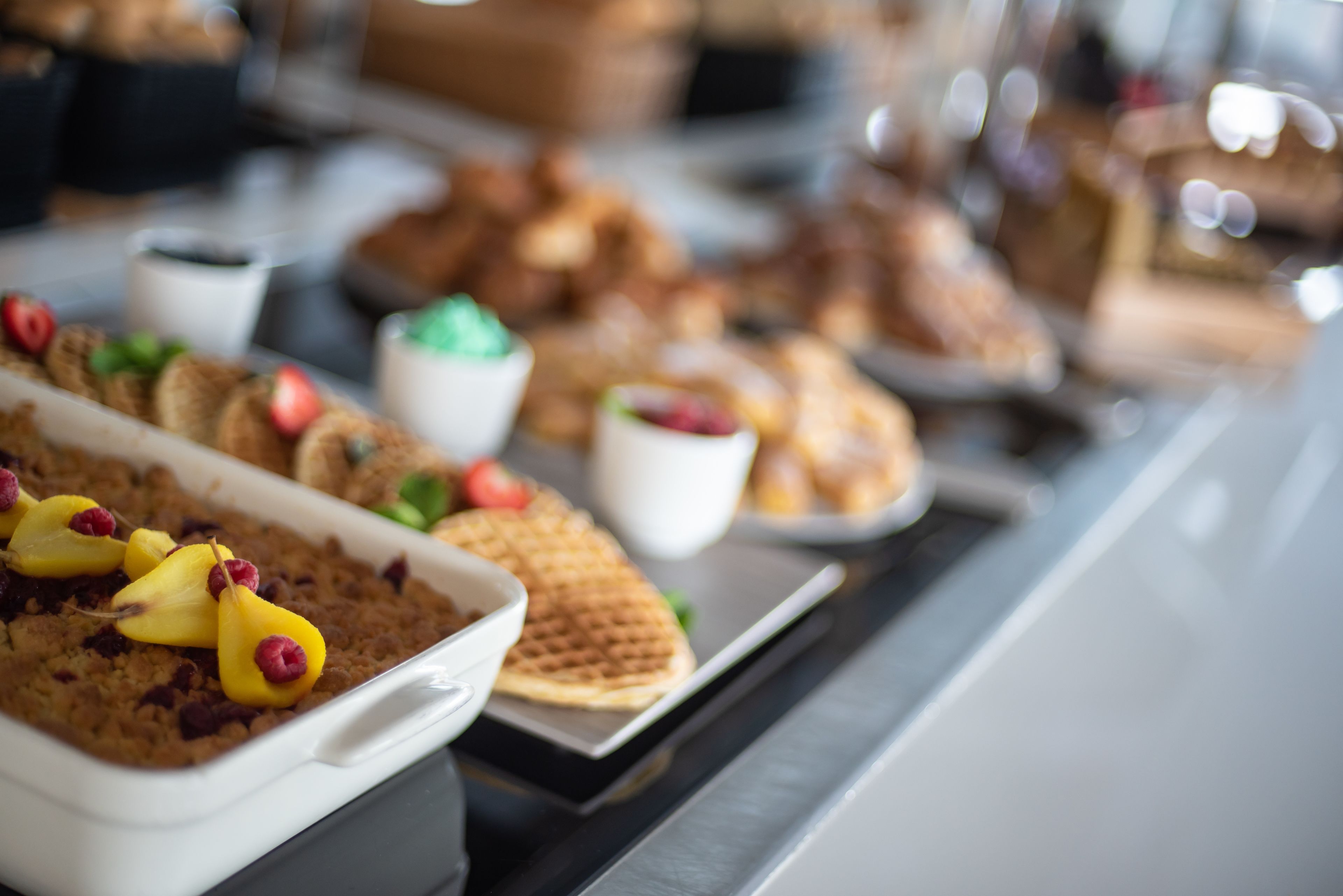 Un bufé con diversos platos, incluyendo un pastel de carne, gofres y postres.