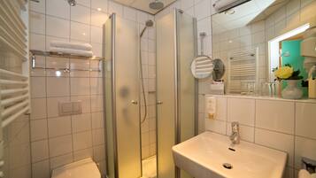 A modern bathroom with a glass-enclosed shower, a white sink, and a toilet.