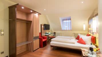 A hotel room with a bed, a desk, a chair, a TV, and a wardrobe.