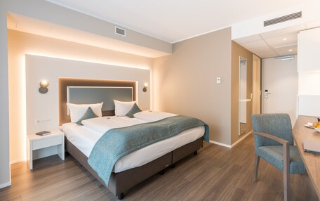 A modern hotel room with a large bed, bedside tables, a desk, and a chair.