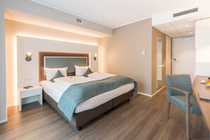 A modern hotel room with a large bed, bedside tables, a desk, and a chair. - Stadthotel Freiburg (Freiburg im Breisgau)