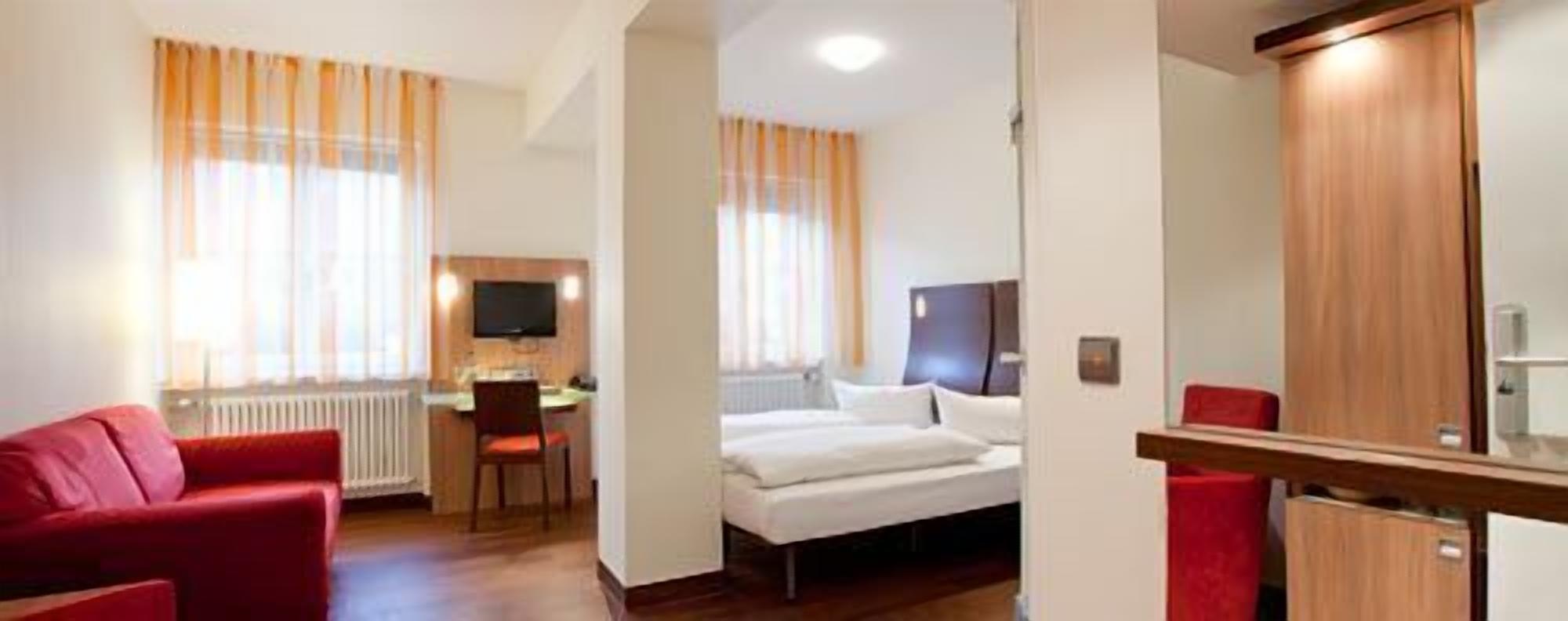 Une chambre d’hôtel comprenant un lit, un bureau avec une chaise, une télévision et une armoire.
