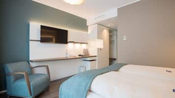 A modern hotel room with a bed, a desk, a chair, and a TV.