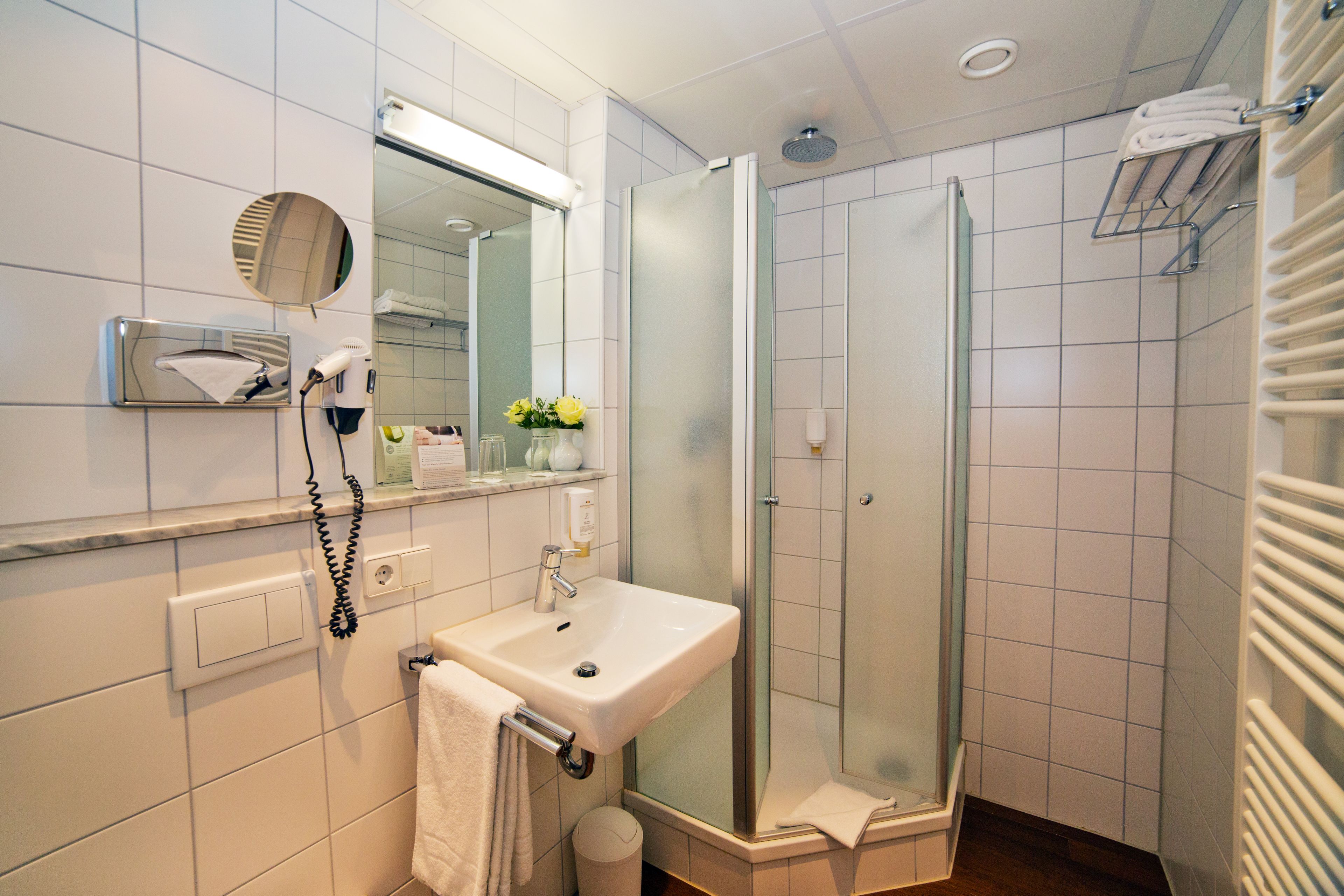 Une salle de bain moderne avec une douche à parois de verre, un lavabo avec un miroir et un porte-serviettes.