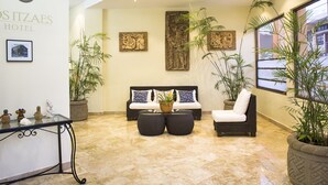 Un hall de hotel con un conjunto de sofás, dos plantas en macetas y una obra de arte colgada en la pared.