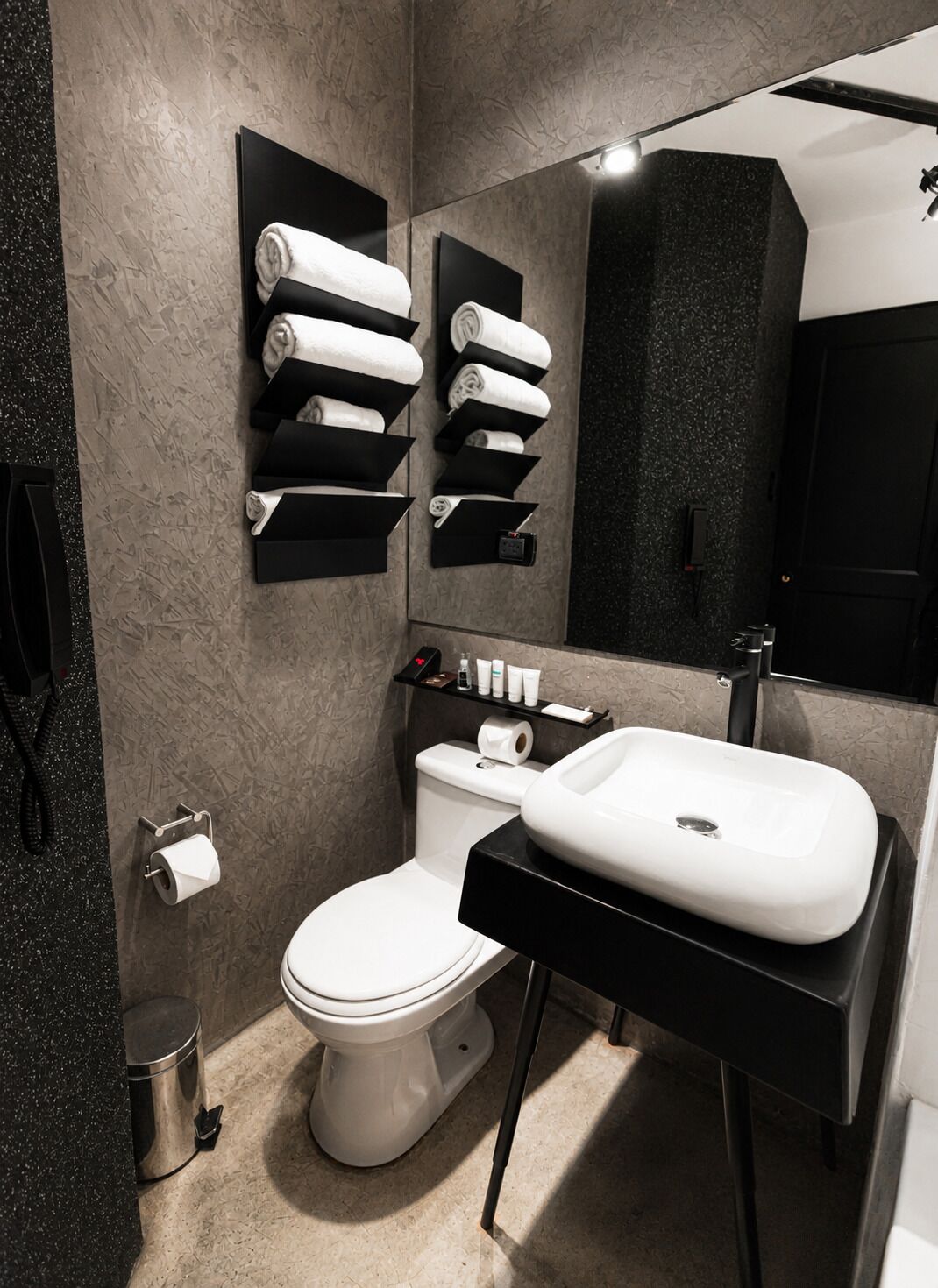 Un baño moderno con inodoro, lavabo, toalleros y espejo.