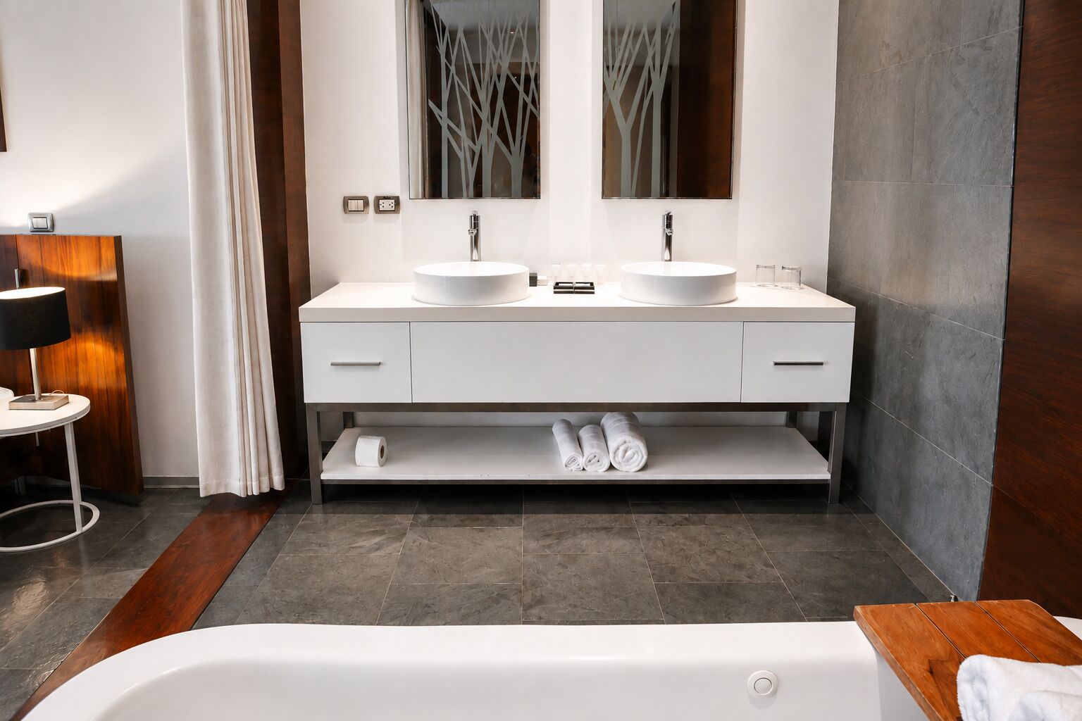 A modern bathroom with a double sink vanity, a bathtub, and a mirror above the sinks.