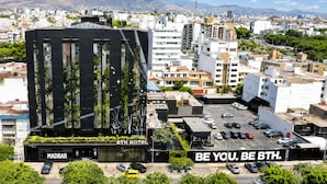 A modern hotel with a black facade, a parking lot, and a slogan 'BE YOU. BE BTH.'