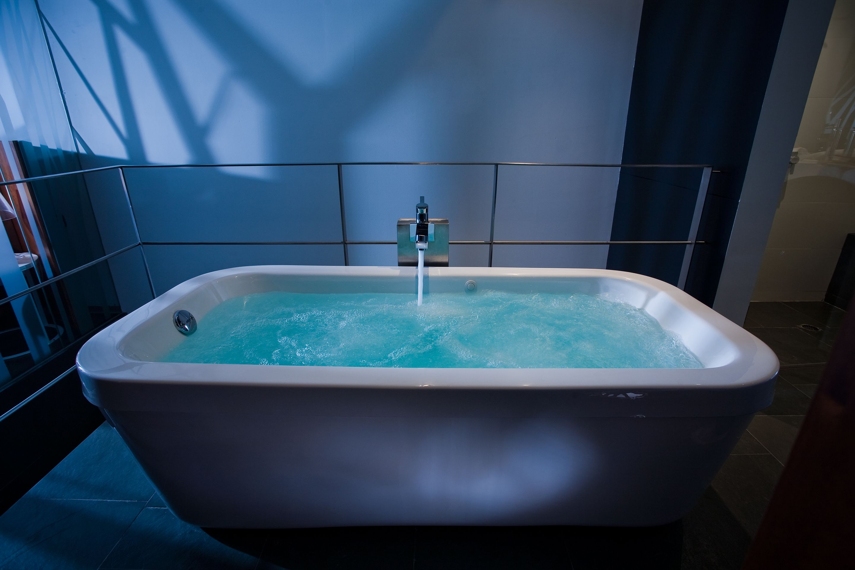 Un baño moderno con una bañera independiente, paredes con azulejos y una zona de ducha visible.