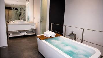 Un baño moderno con una bañera grande, un tocador con espejo y un estante con toallas.
