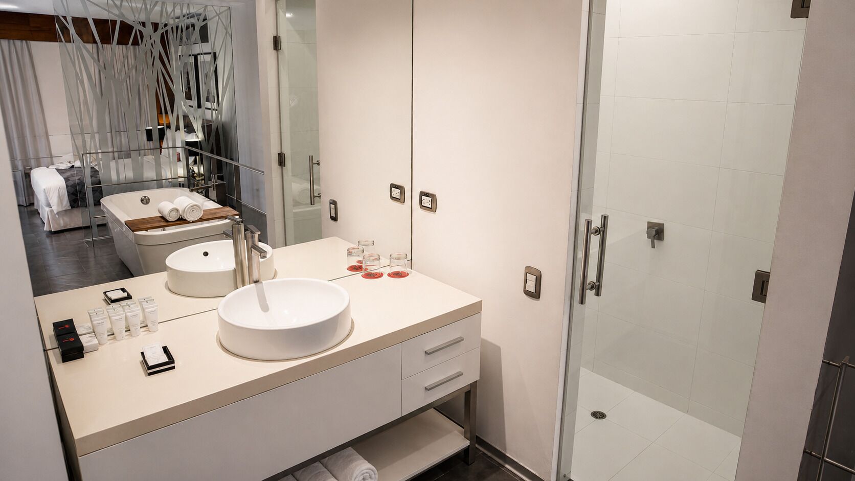 A modern bathroom with a large sink, a mirror, and a glass shower enclosure.