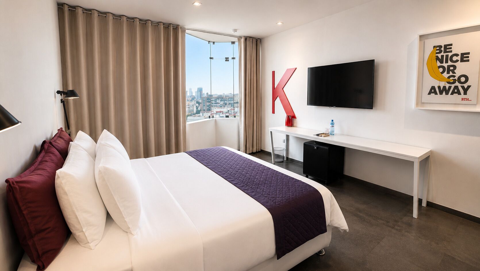 A hotel room with a bed, a desk, a TV, and a large window with a city view.