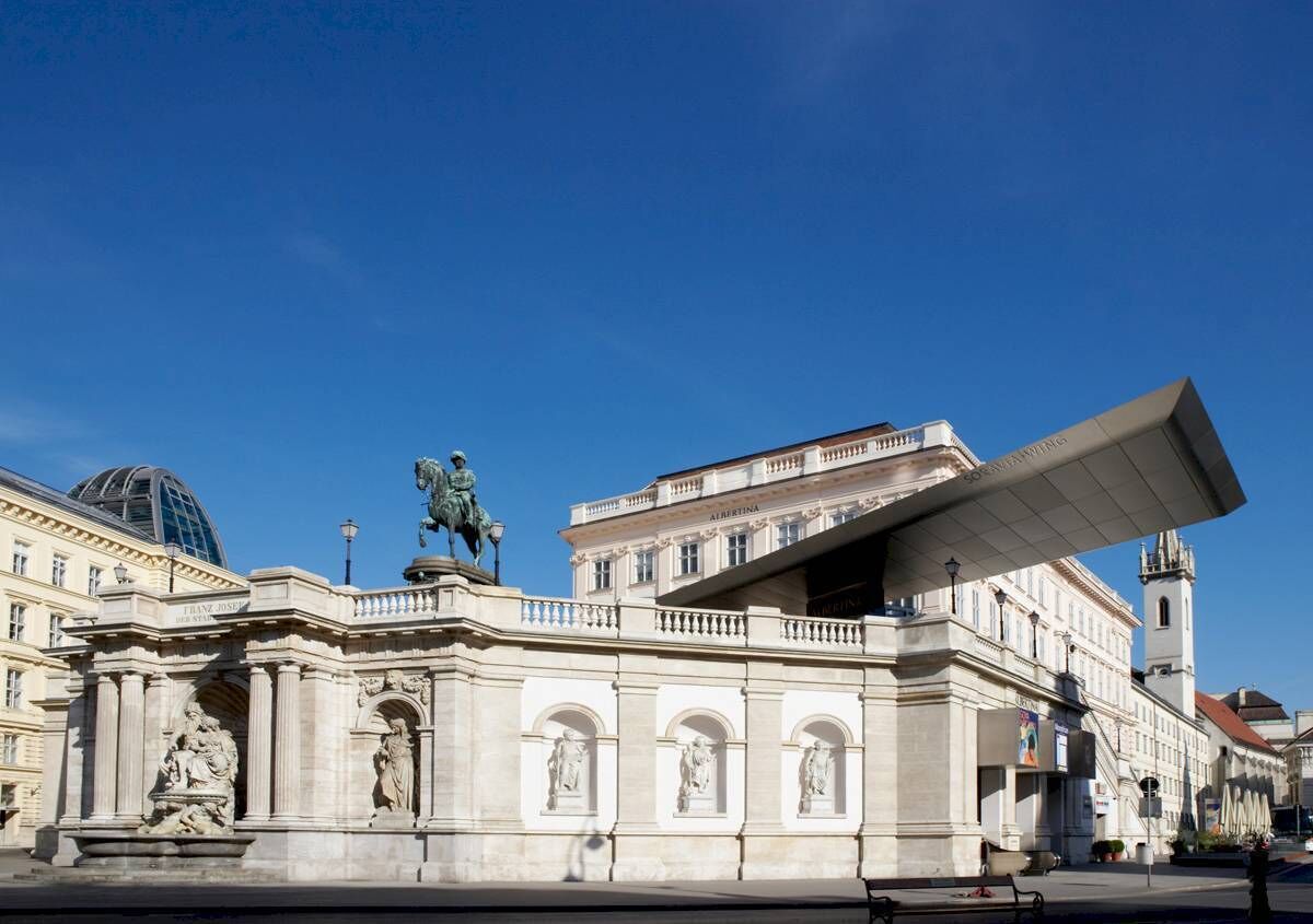 A historic building with classical architecture, featuring statues and a prominent dome.