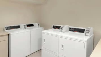 A laundry room with two white front-loading washing machines and dryers.