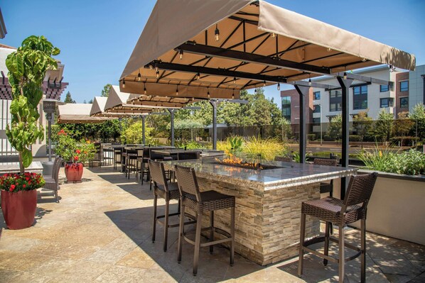 An outdoor patio with a stone bar, wicker chairs, and a covered seating area. - Courtyard Palo Alto Los Altos (Los Altos)