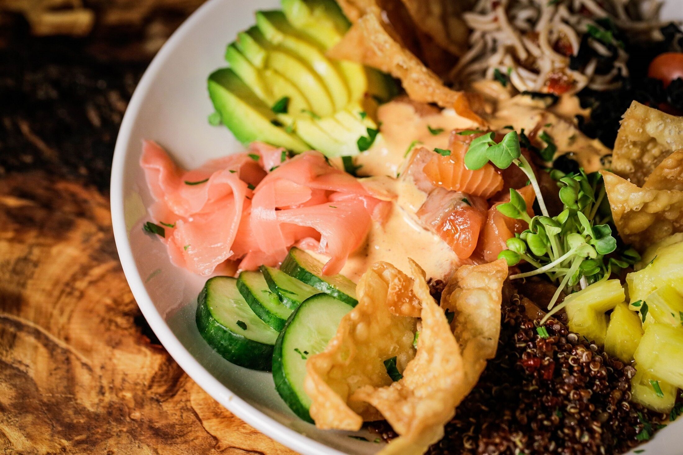 A bowl of food with various ingredients like salmon, avocado, and vegetables.