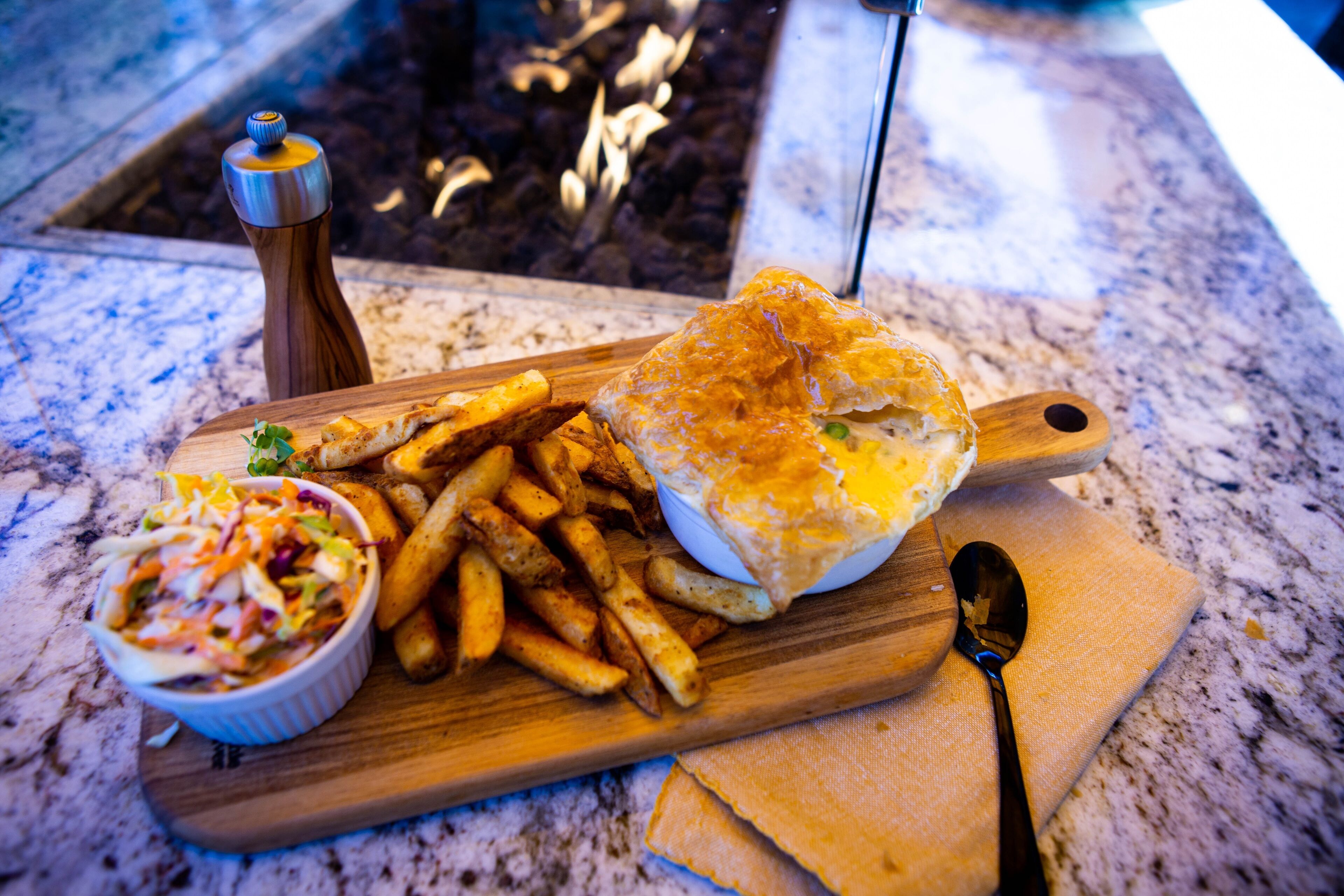 A meal consisting of a sandwich, fries, and a side salad on a wooden board.