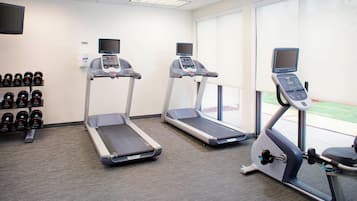 Academia com esteiras, máquinas de musculação e halteres.