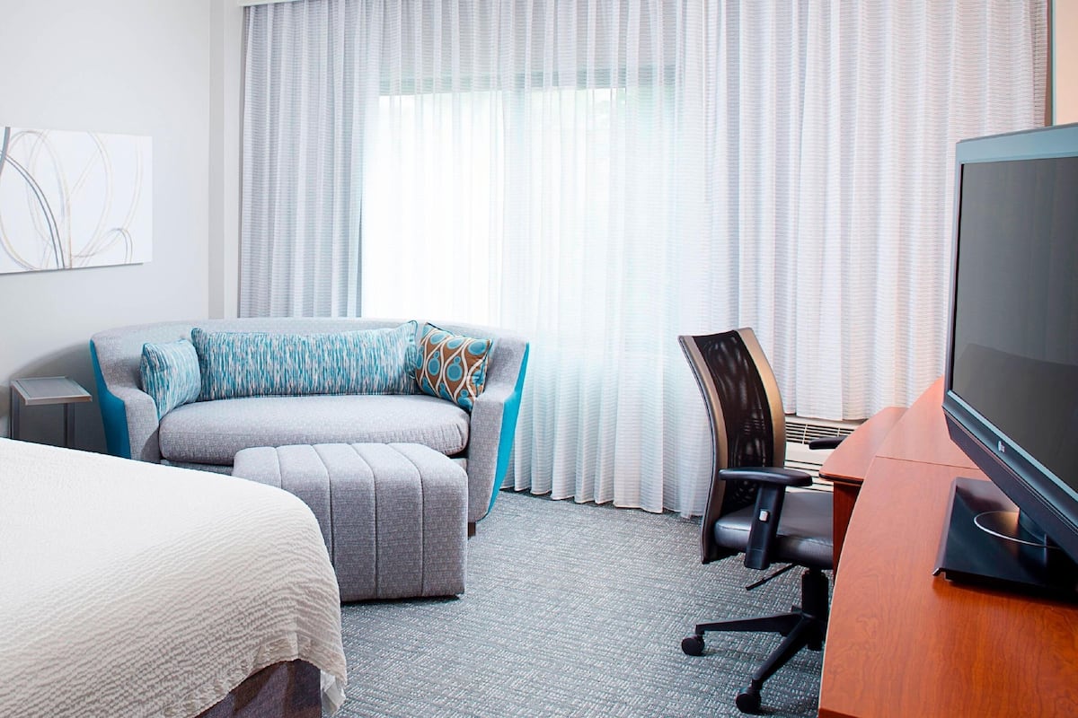 Une chambre d’hôtel comprenant un lit, un canapé, un bureau avec une télévision et une chaise.